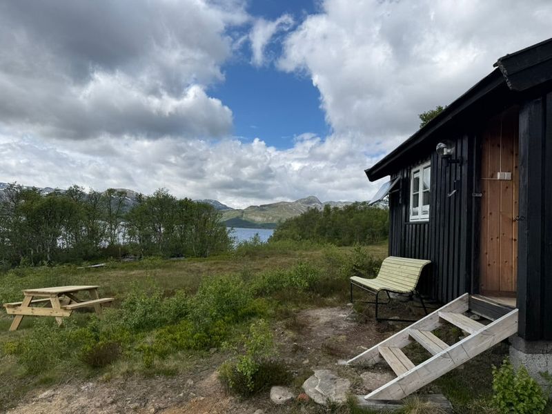 Bonserud med bord og stol utenfor døra, og Møsvatn like bak i bakgrunnen