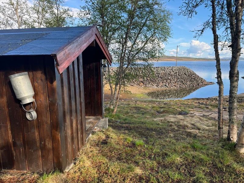 Uthuset ved Knøttebu, med Møsvatn og steinmoloen bak trærne