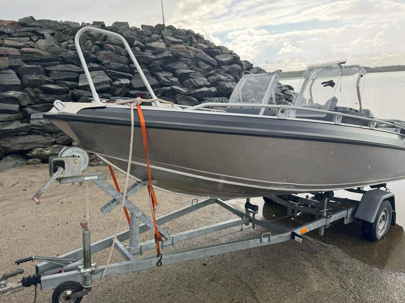 Aluminiumsbåt på henger satt opp mot en steinmur ved kaia på Førnes